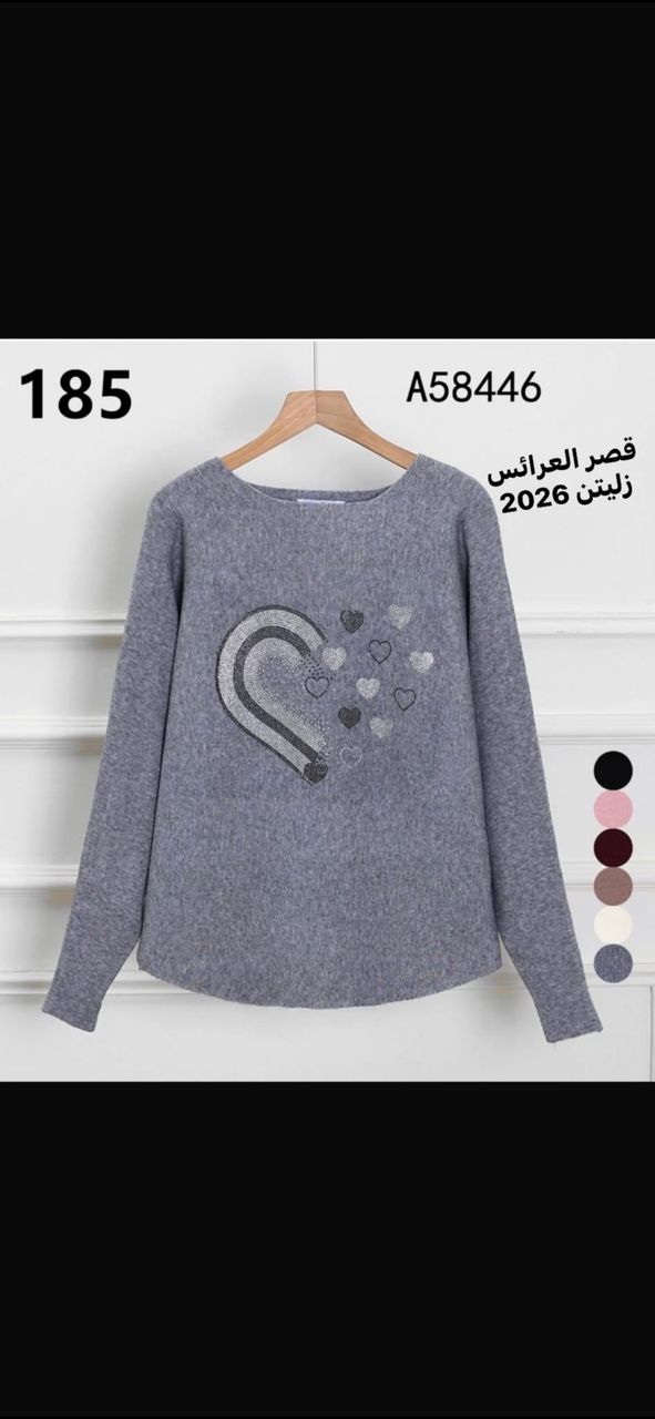 امرأة ترتدي طقماً أنيقاً مكوناً من بلوزة وسروال، تقف في متجر ملابس مع خلفية تعرض مجموعة متنوعة من الأزياء. النص الموجود في الصورة يقرأ قصر العرائس زليتن 2026، مما يضفي طابعاً عصريًا وثقة على المشهد.